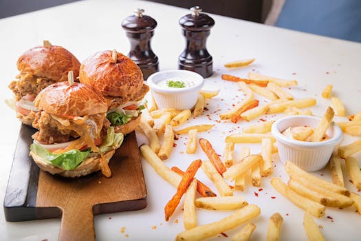 Delicious gourmet burgers and crispy fries served on a wooden board, perfect for fast food lovers.