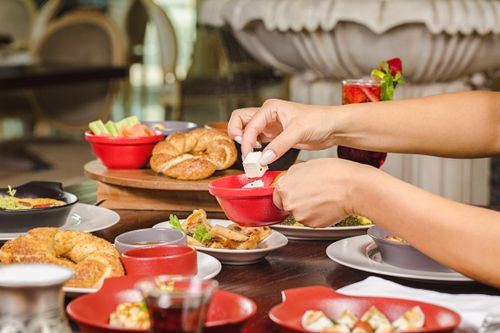 Free Hands preparing Middle Eastern breakfast with bread, dips, and tea in a Dubai restaurant setting. Stock Photo