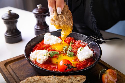 Free Close-up of shakshuka with poached egg, tomatoes, and bread in a cast iron skillet. Stock Photo