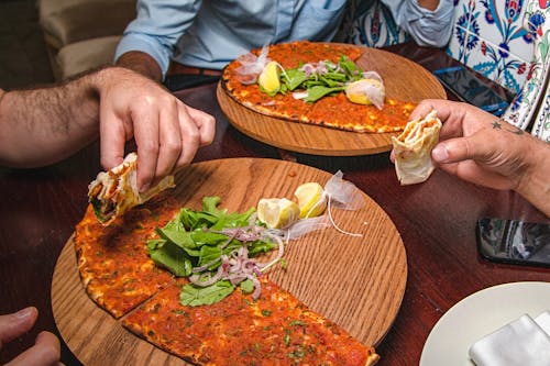 People Holding Pizzas