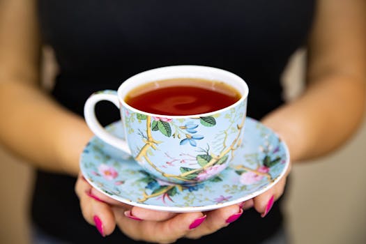 Close-up of an elegant floral teacup and saucer being held, perfect for tea lovers.