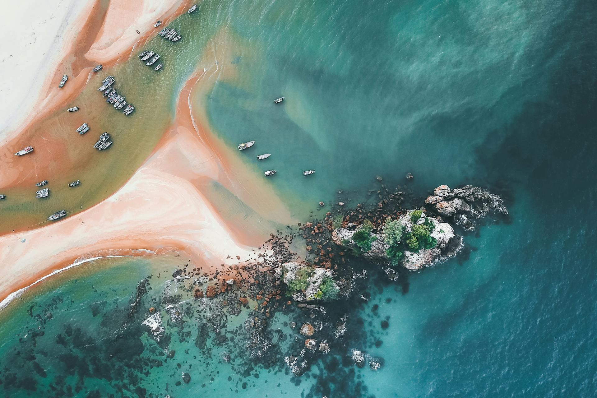 Spectacular drone view of boats floating on surface of turquoise ocean water washing sandy beach on sunny day