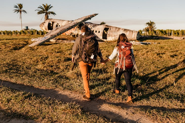 Unrecognizable Tourists Walking On Land Near Crashed Airplane