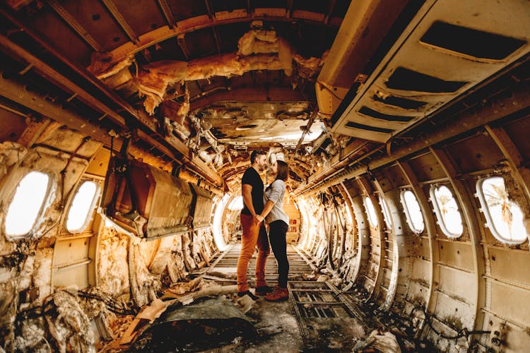 Unrecognizable Couple Holding Hands In Damaged Plane Interior