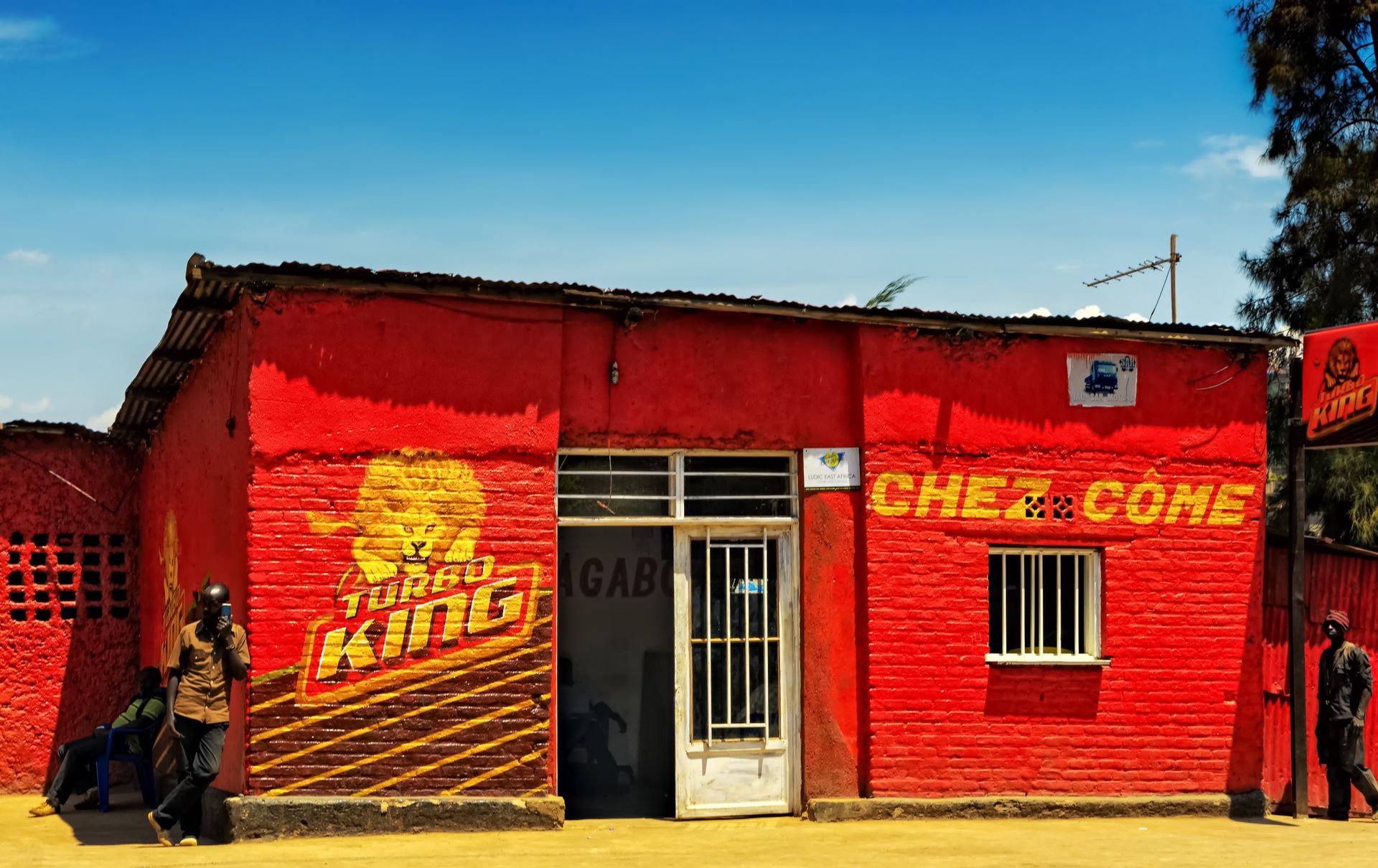 Bright red building with betting shop signs in a bustling Kigali street, Rwanda.