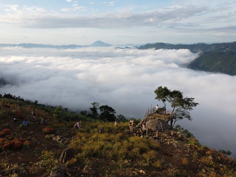 High angle of people on observing cloudy nature from grassy hill edge in highlands
