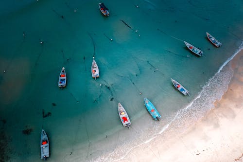 Boats floating near sandy sea coast