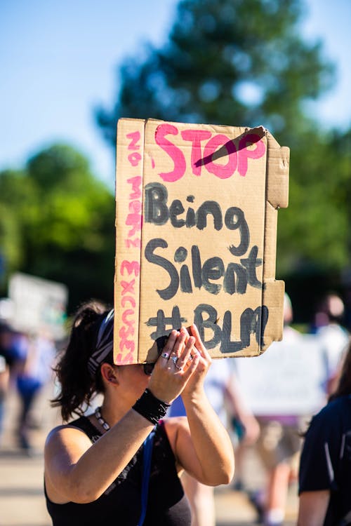 Unrecognizable social justice warrior demonstrating placard with inscription while fighting for equality in town