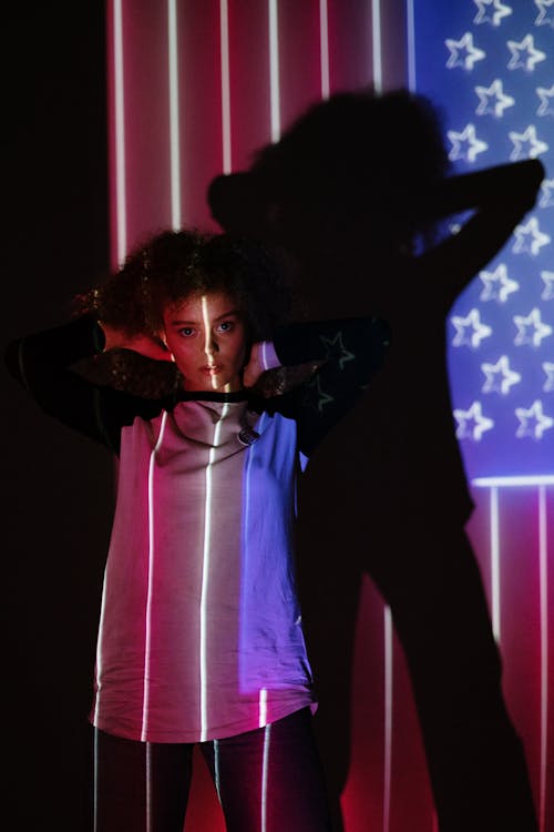 Free Woman Standing in Front of a Projection of the American Flag Stock Photo
