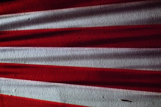 Close-up of a textured American flag surface with dramatic lighting creating abstract shadows.