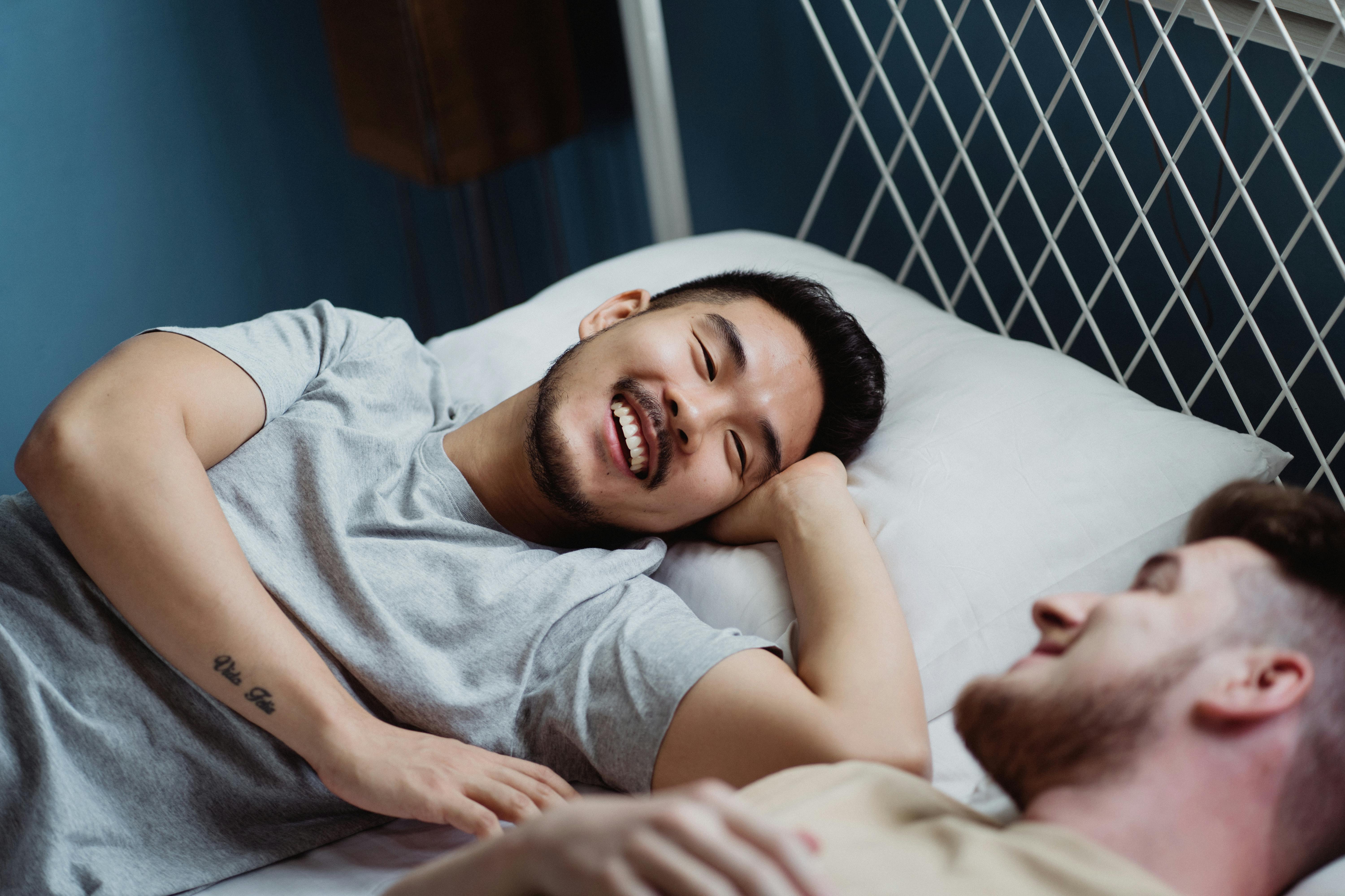 two men in bed looking at each other