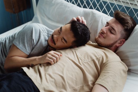 A loving gay couple enjoying a moment of intimacy and relaxation while reclining together in bed.