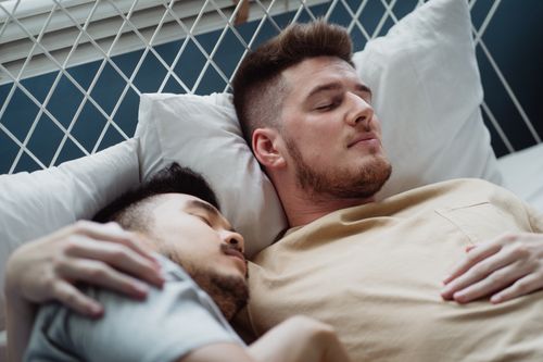 Free Peaceful scene of a loving interracial couple sleeping together in bed, surrounded by pillows. Stock Photo