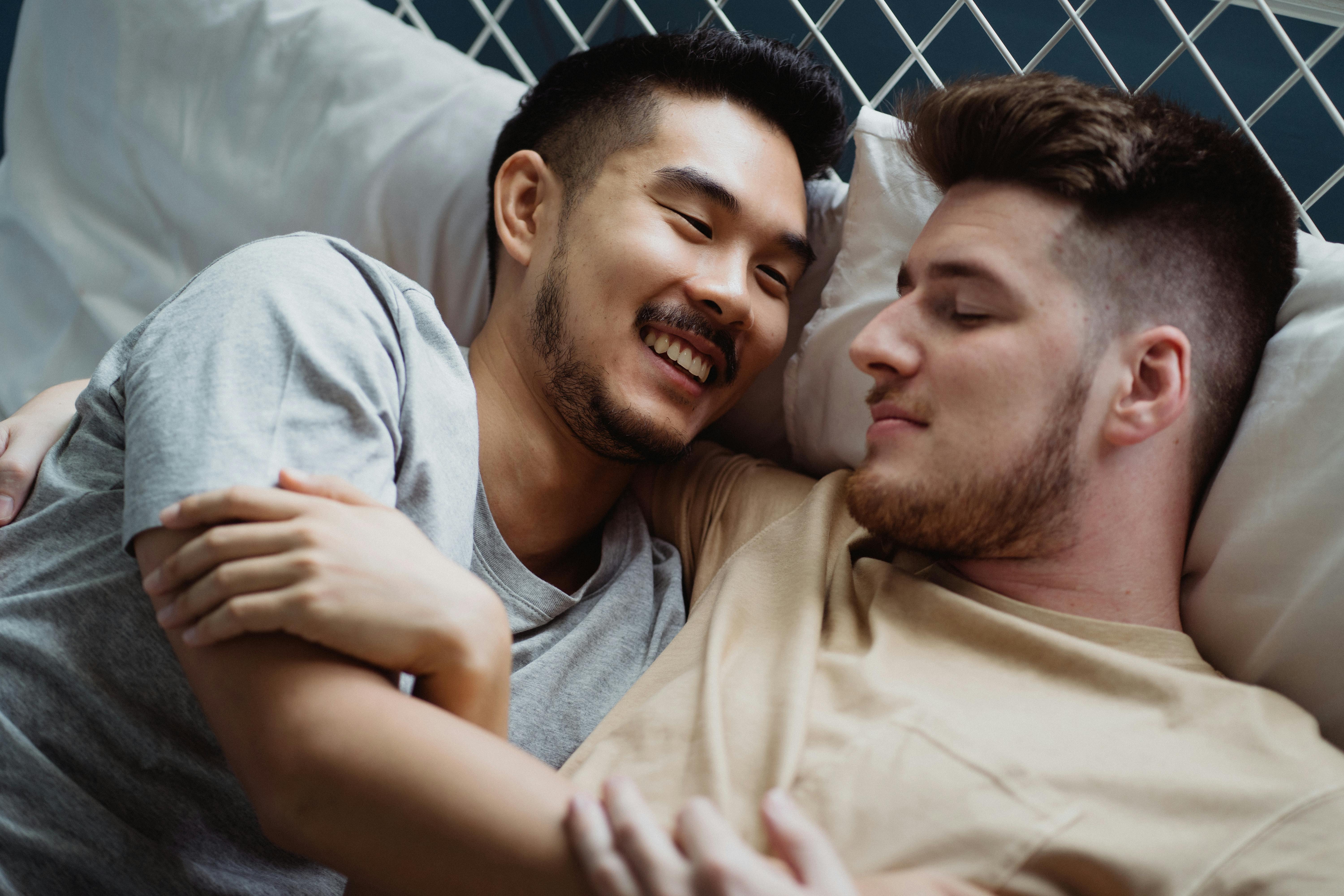 two men cuddling in bed