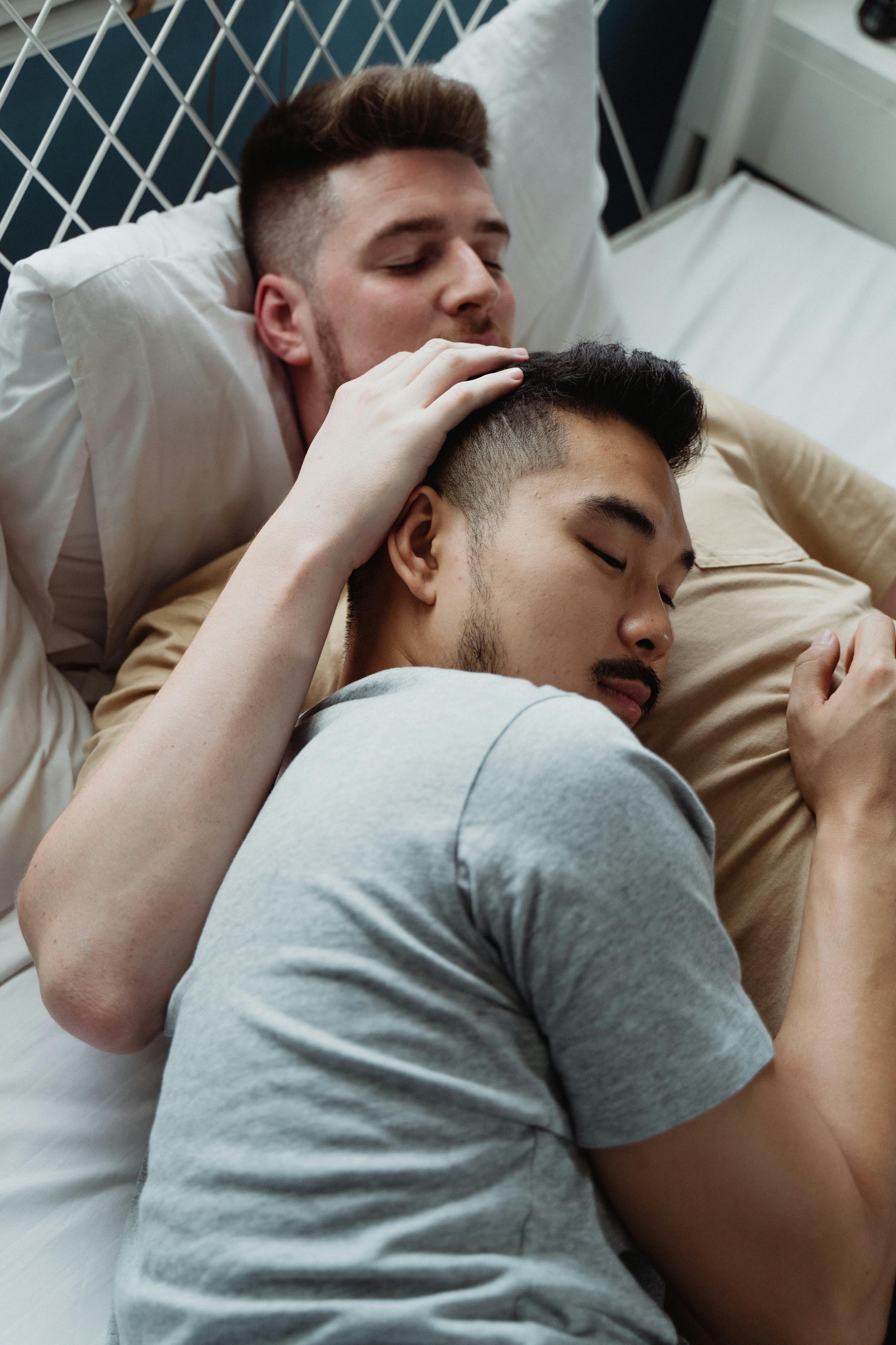 two men in bed cuddling