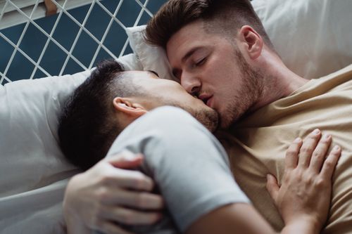 Free A romantic moment captured as a couple shares a tender kiss while lying in bed. Stock Photo