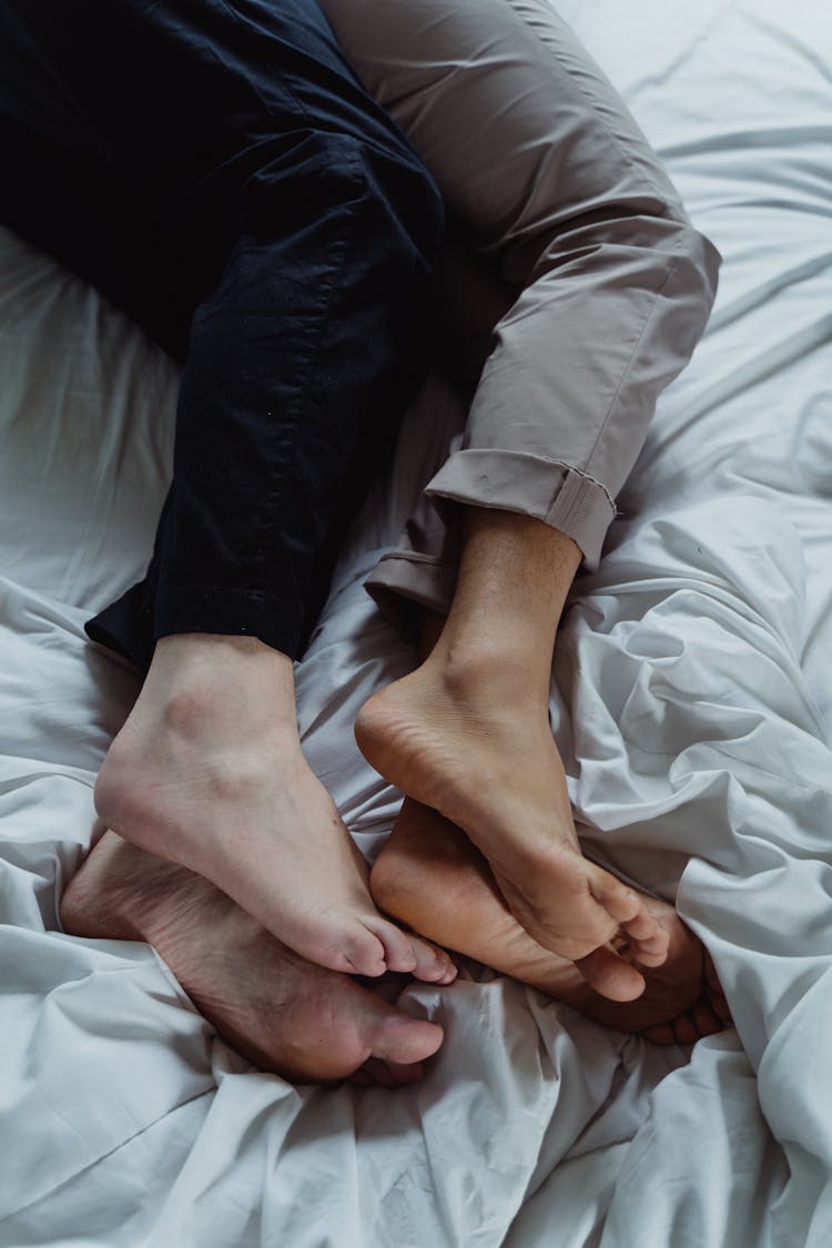 Feet Of A Couple Lying Down In Bed