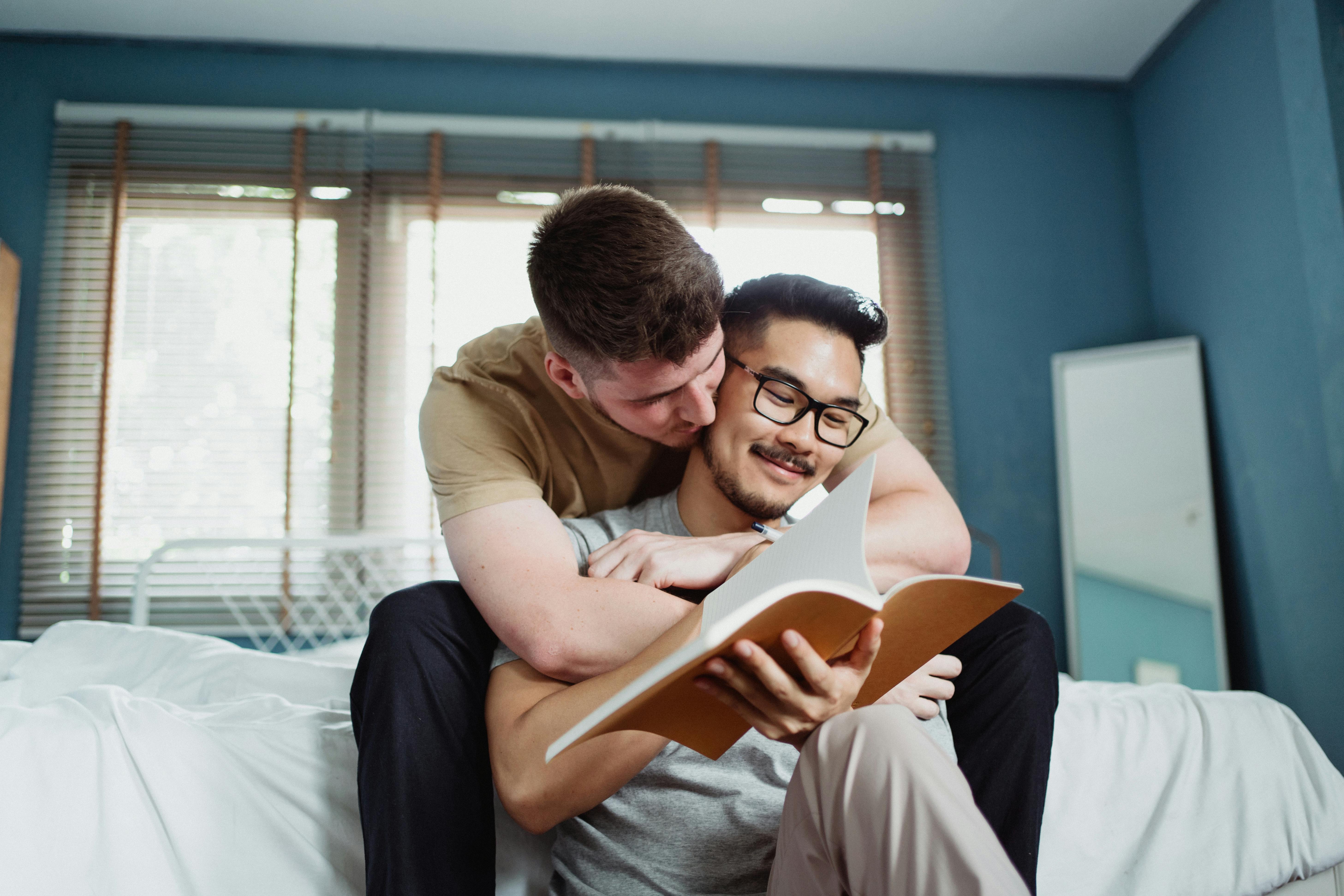 man reading and being embraced by another man