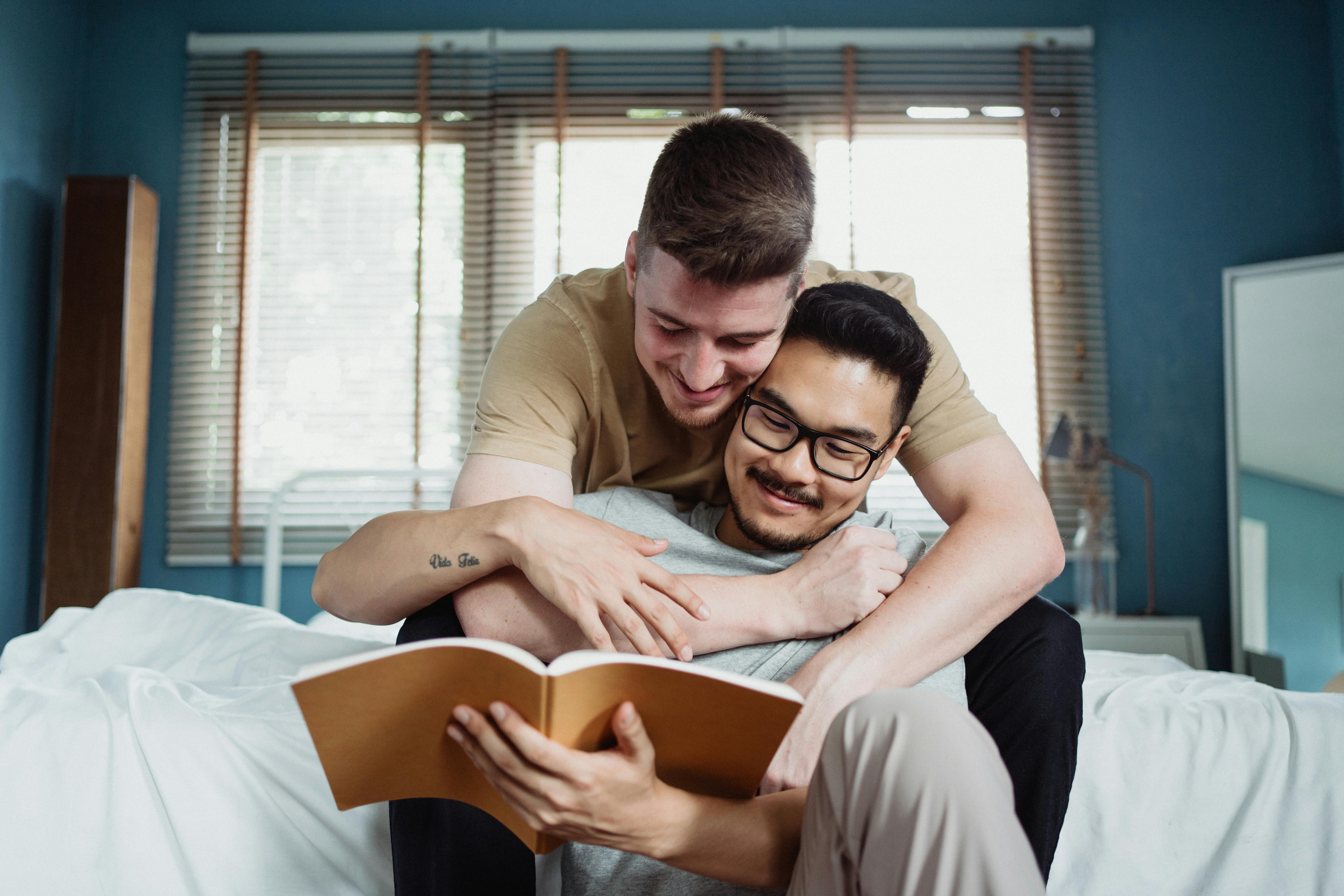 two men reading a book and being affectionate