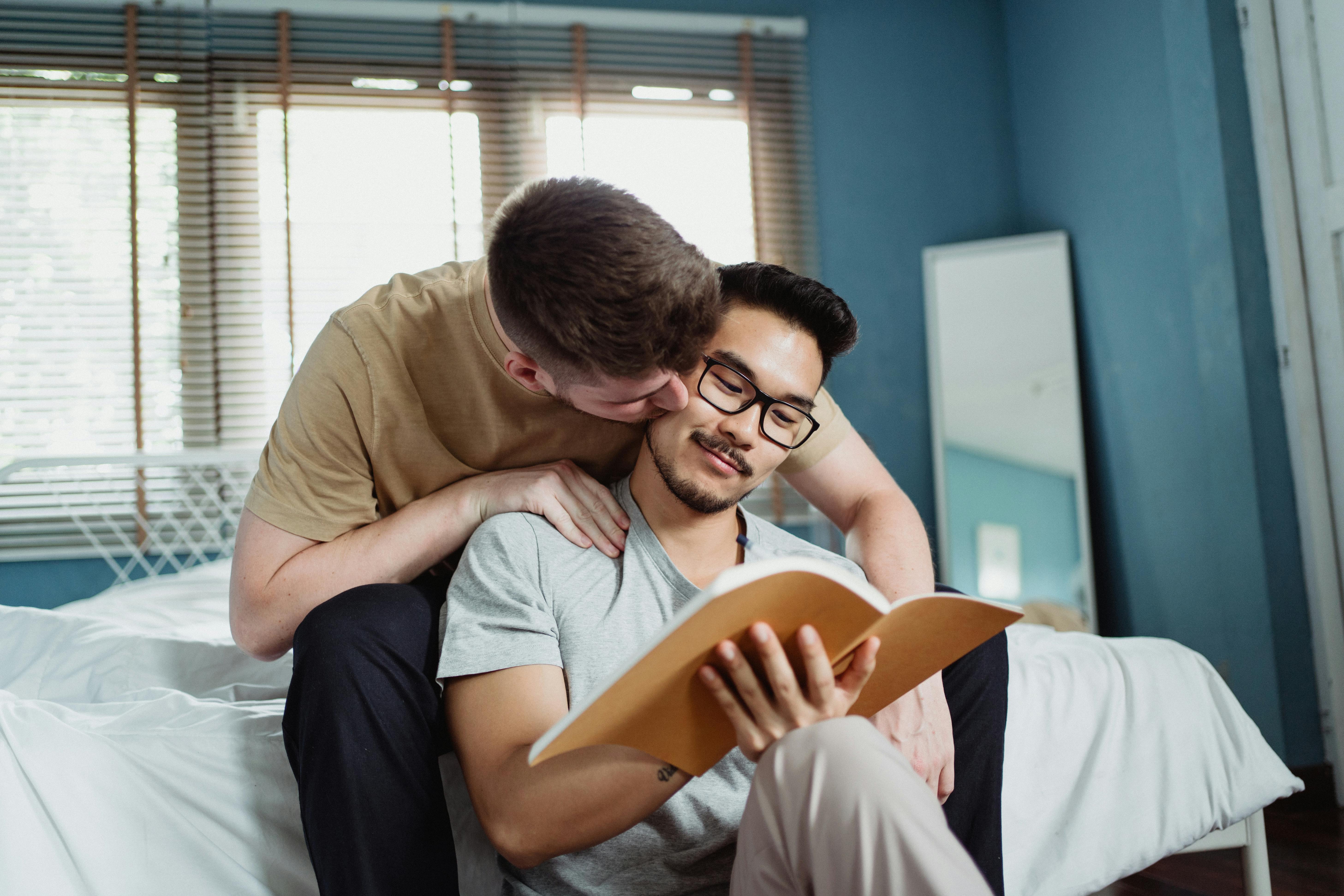 man reading a book and being kissed on the cheek