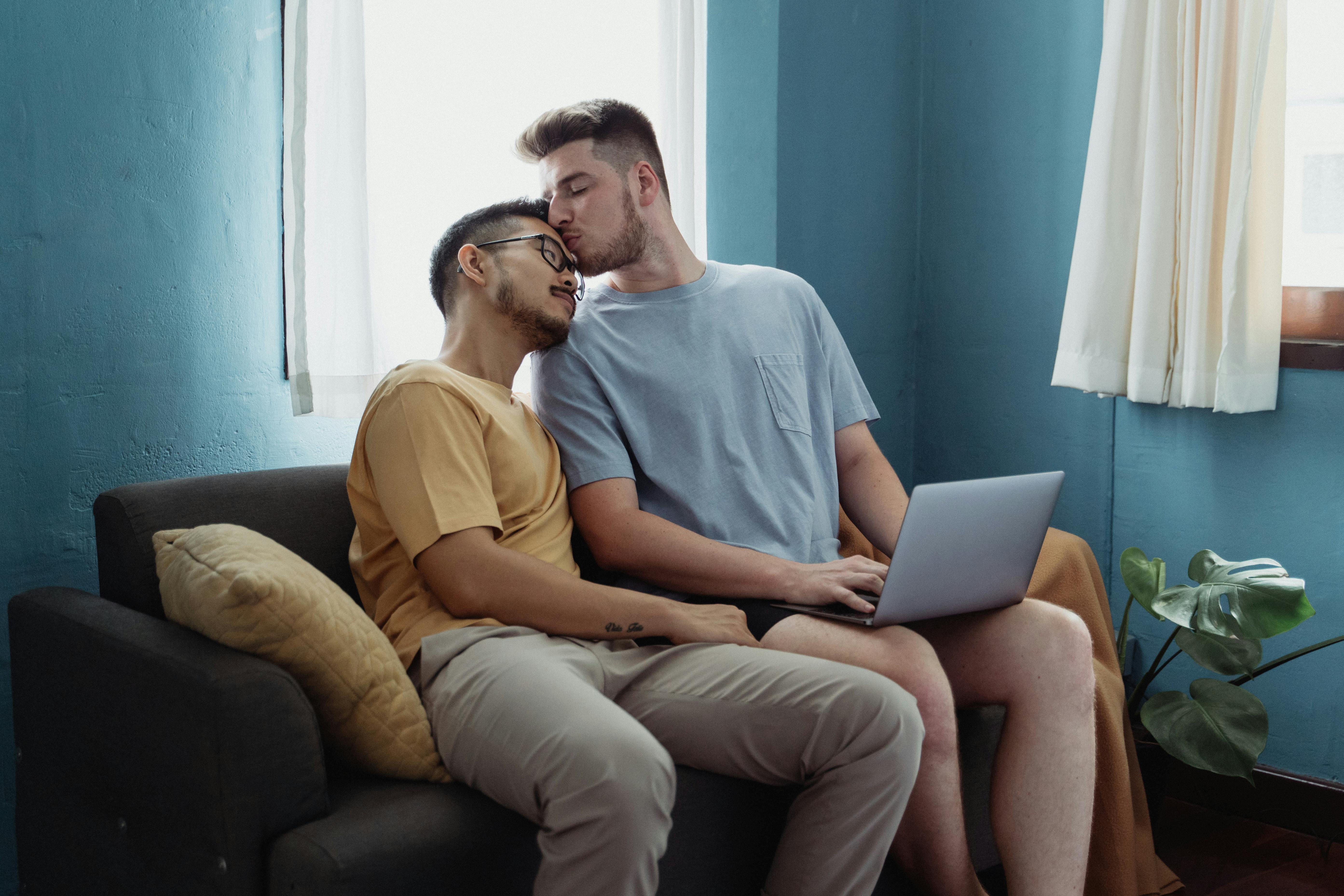 man kissing another man on the forehead