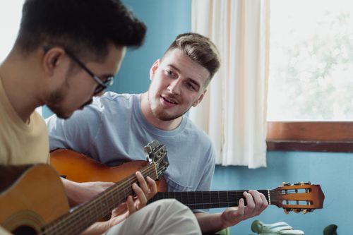 Free Two men enjoying playing acoustic guitars together in a cozy indoor setting. Stock Photo
