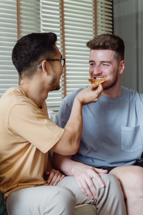 Man Feeding Pizza to Another Man