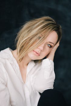 一位留着时髦短发的白人女性，身着白衬衫，摆出了一个优雅的姿势