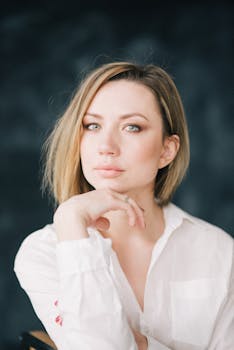 一位留着金色短发的白人女子摆出时尚肖像的姿势，手放在下巴上