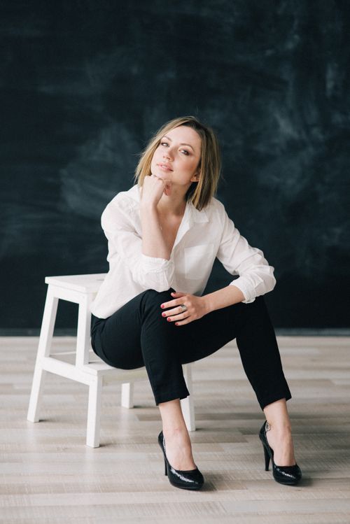 Free Portrait of a stylish woman sitting on a chair in an elegant and confident pose indoors. Stock Photo