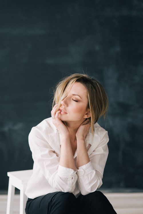Free Woman in white shirt posing gracefully indoors against a dark background. Stock Photo