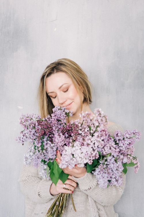 Free Peaceful woman with short blonde hair holding lilac flowers, eyes closed in bliss. Stock Photo