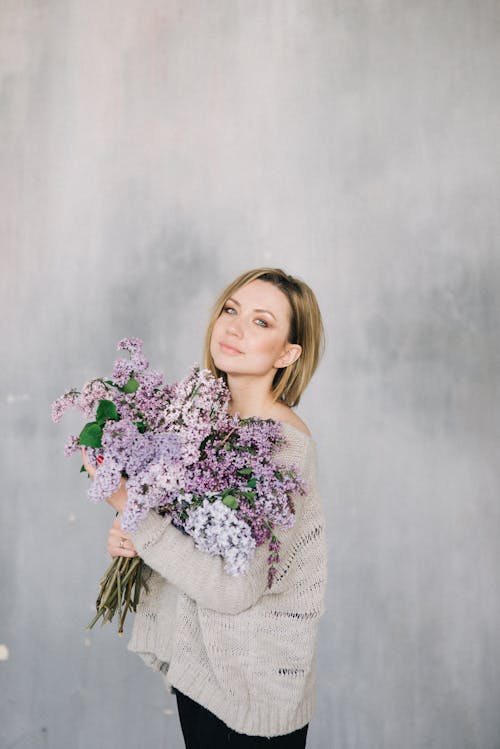 Woman in Knitted Sweater Holding a Bunch Lilac Flowers