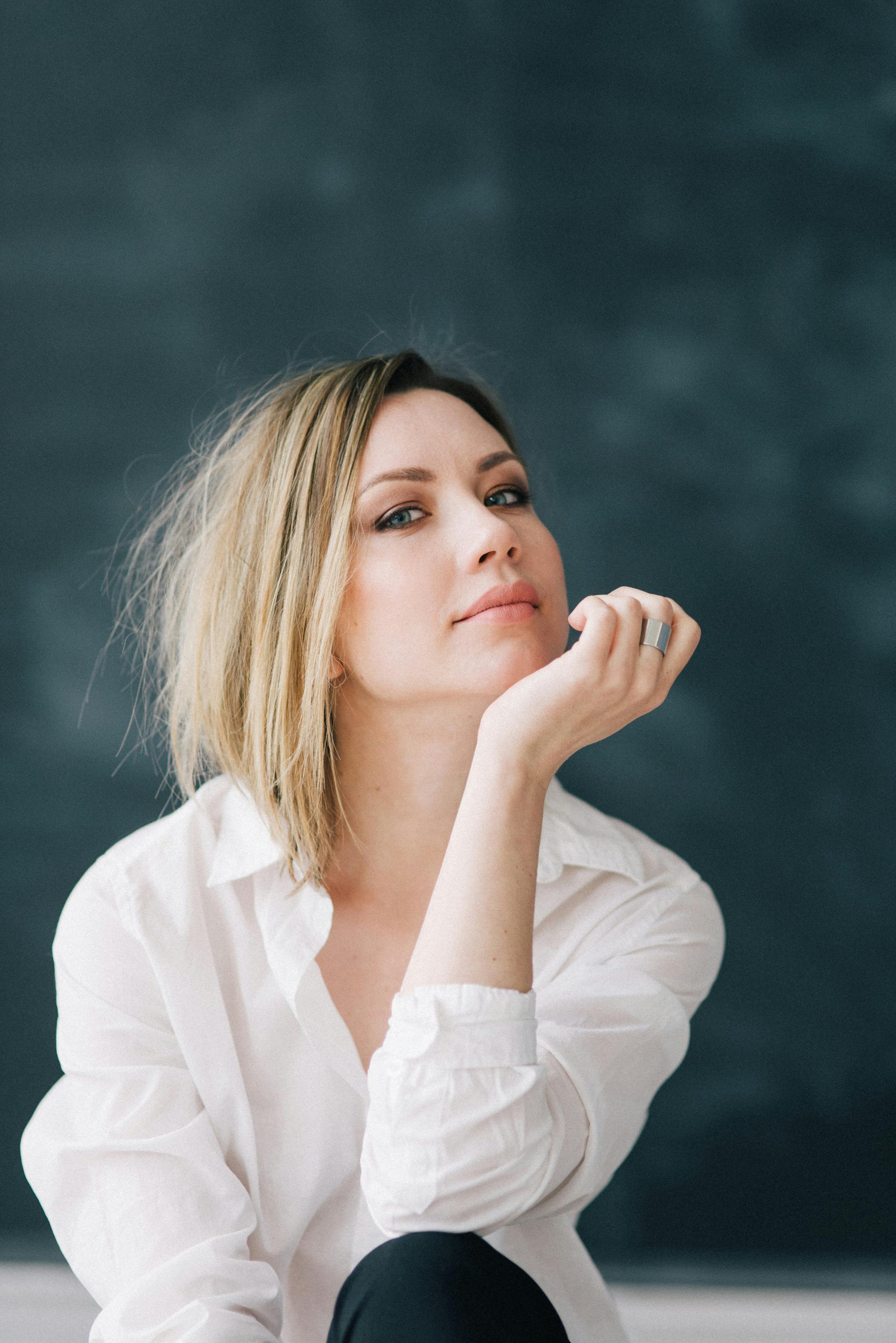 一位穿着白衬衫的白人妇女在室内优雅地摆着姿势，肖像中她表情若有所思