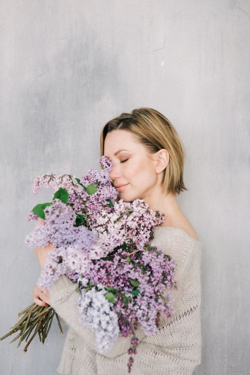 Free Blonde woman with short hair embraces lilacs, eyes closed, conveying tranquility. Stock Photo