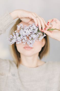 一个女人拿着丁香花，平静而柔和地遮住了脸