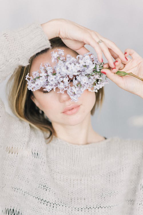 흰 꽃 꽃다발을 들고 흰색 니트 스웨터에 여자