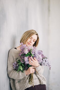 一位金色短发的宁静女人，手拿一束丁香花，背景柔和