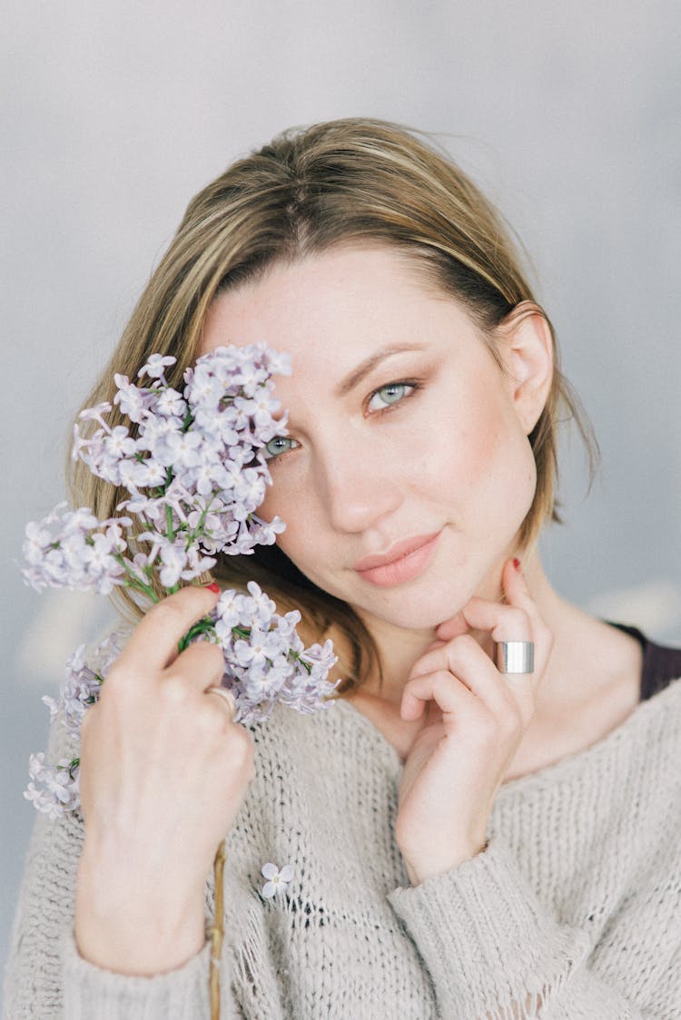 Woman Holding Small Flowers Near To Her Face