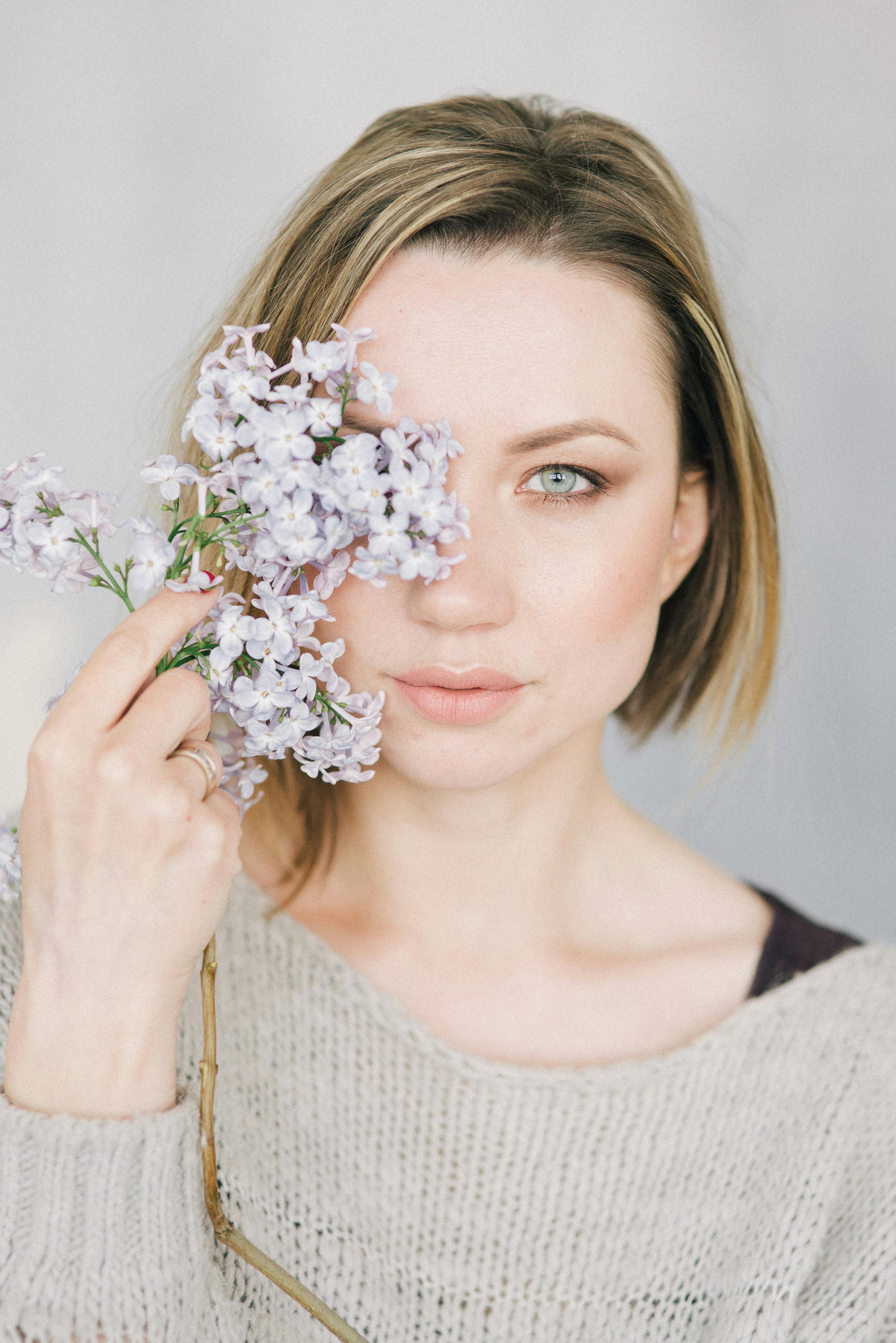 一位穿着针织毛衣的女人手持丁香花的柔焦肖像