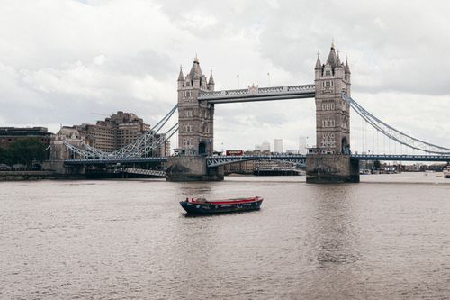 Free Explore the iconic Tower Bridge spanning the River Thames under a cloudy sky in London. Stock Photo