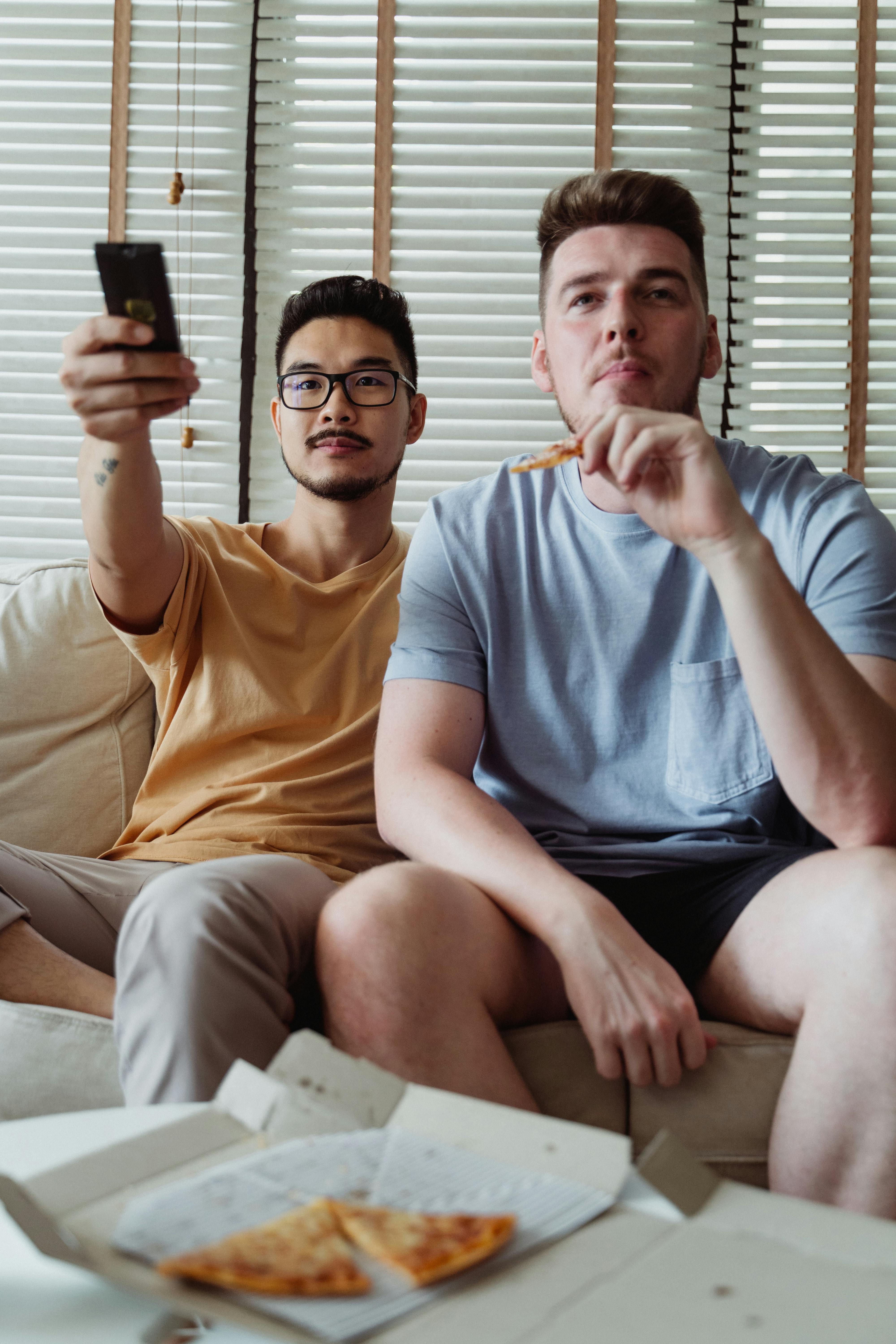 two men eating while watching tv