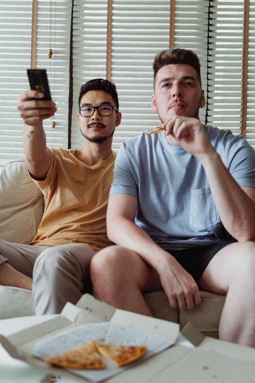 Free Two Men Eating While Watching Tv Stock Photo