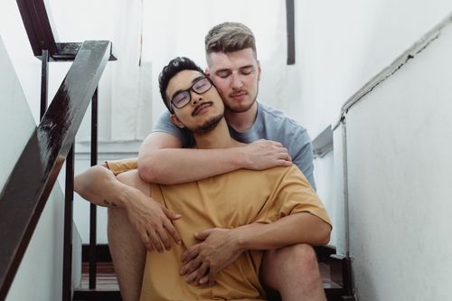 Free An interracial gay couple embracing intimately on a staircase, expressing love and togetherness. Stock Photo