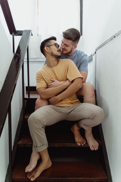 Free A loving gay couple embracing on stairs, showcasing interracial love and LGBTQ+ pride. Stock Photo