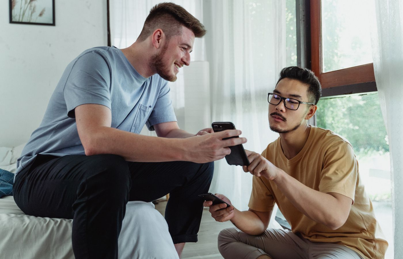 Two young men using smartphones, collaborating in a cozy room setting.