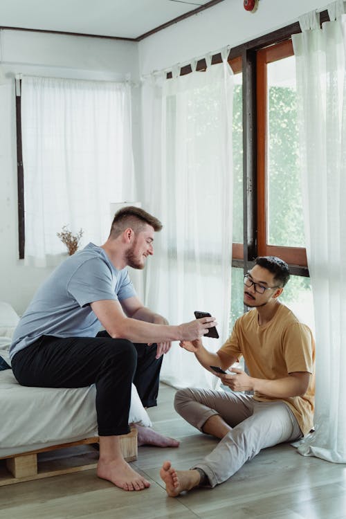 Free Man Showing his Cellphone to the Person with Eyeglasses Stock Photo