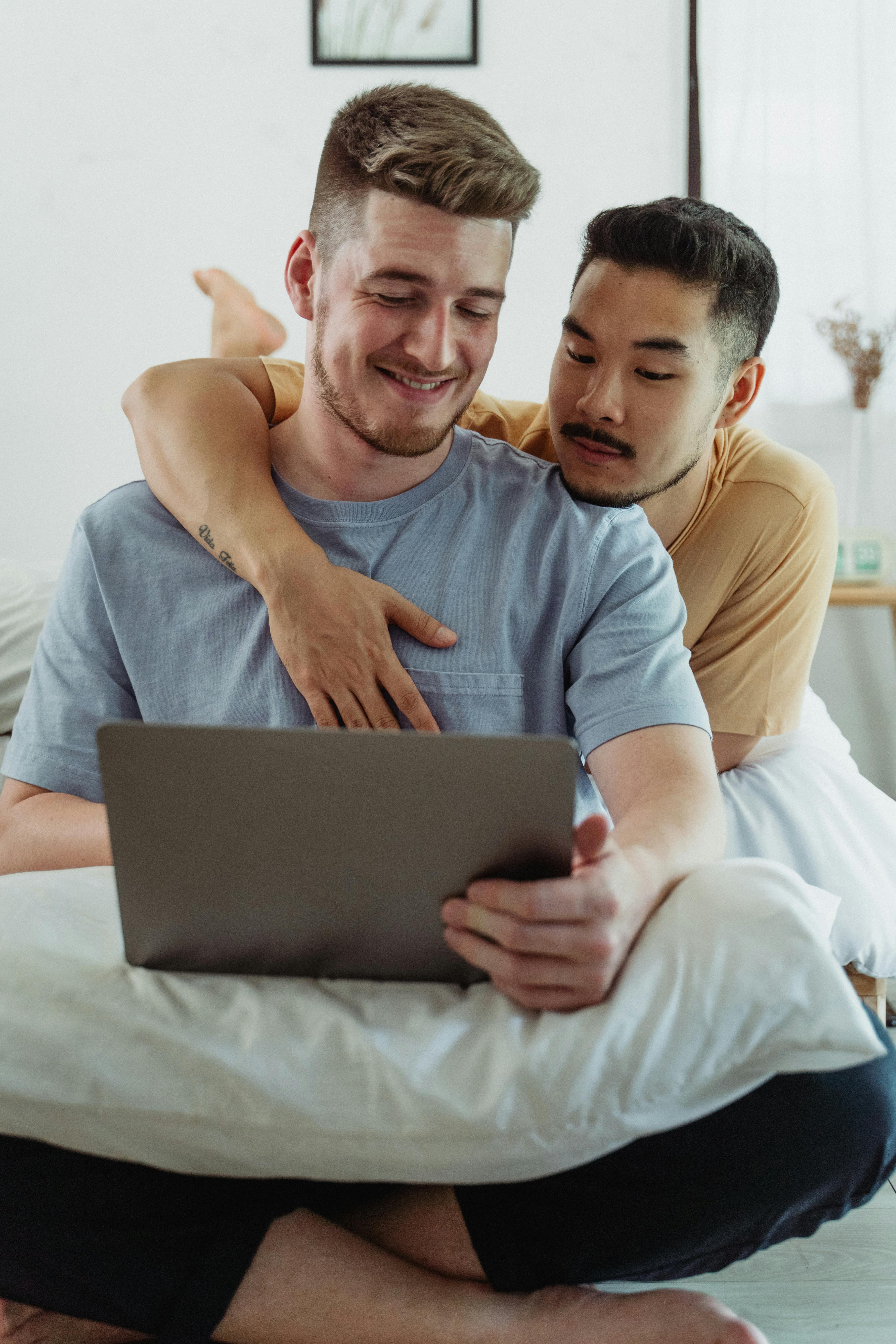two men being affectionate and looking at a laptop