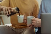 两个成年人在室内一起倒咖啡、喝咖啡，气氛轻松