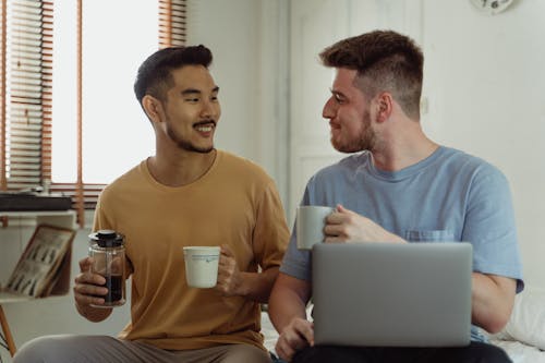 Men Looking at each other while Holding Ceramic Mugs